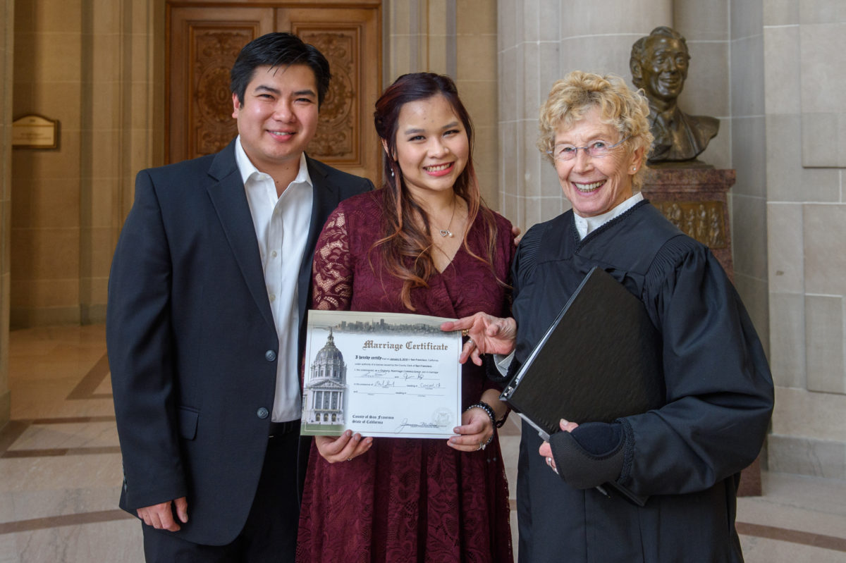 Happy Bride and Groom with Marriage Certificate and officiant 