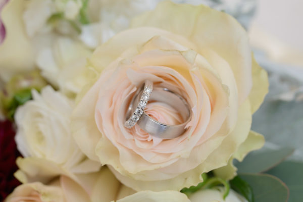 Close up of the wedding rings with a rose