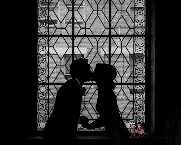 Silhouette images of bride and groom in window