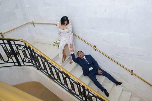 Funny wedding photography as bride drags groom up the stairs