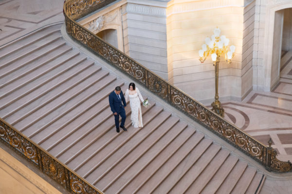 Groom escorts his new bride down the Grant Staircase at SF City Hall