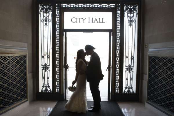 Wedding kiss at San Francisco city hall entrance door.
