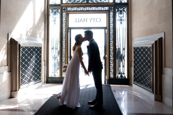 bride and groom kissing at SF city hall exit