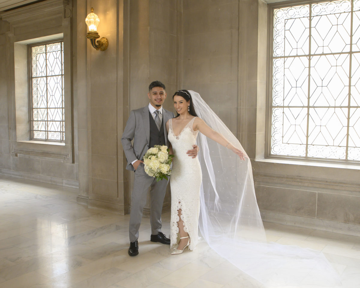 Bride and groom posing near decorative window at San Francisco city hall 