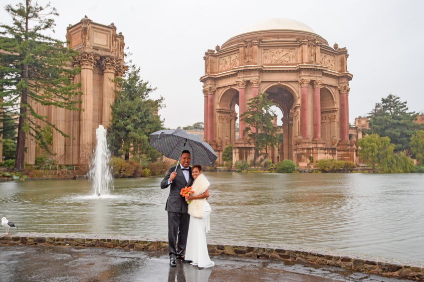 Palace of Fine Arts on a rainy day with bride and groom under umbrella