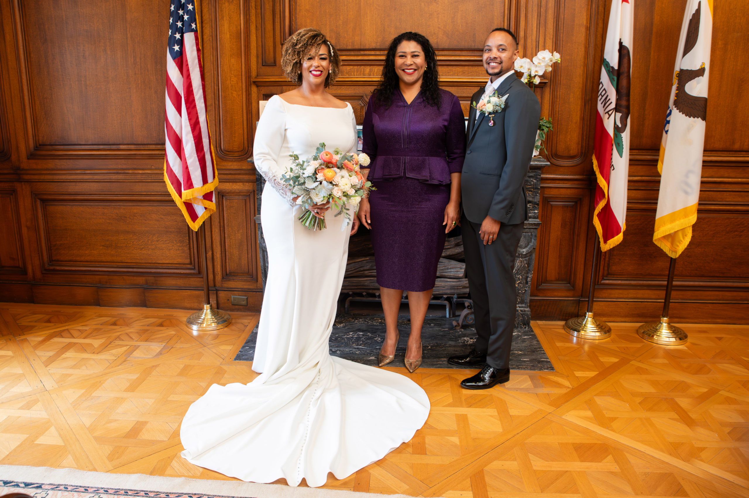 San Francisco Mayor, London Breed posing with the bride and groom in her office