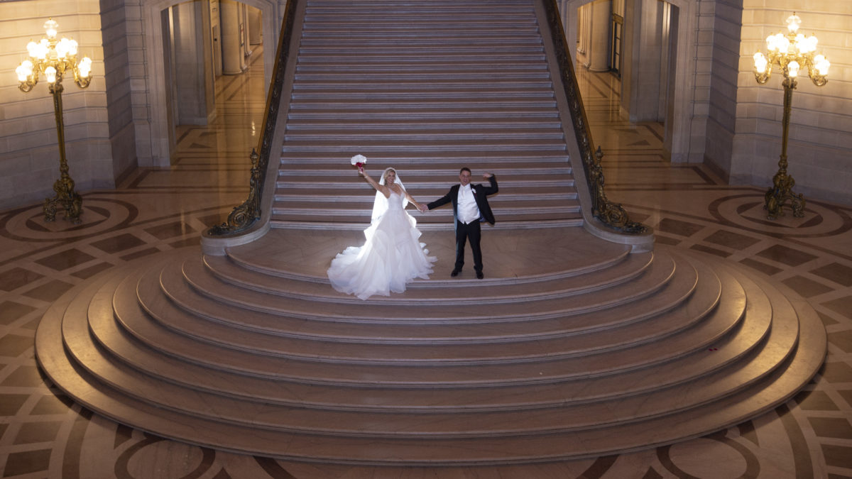 SF City Hall Bride and Groom celebrate on the Grand Staircase