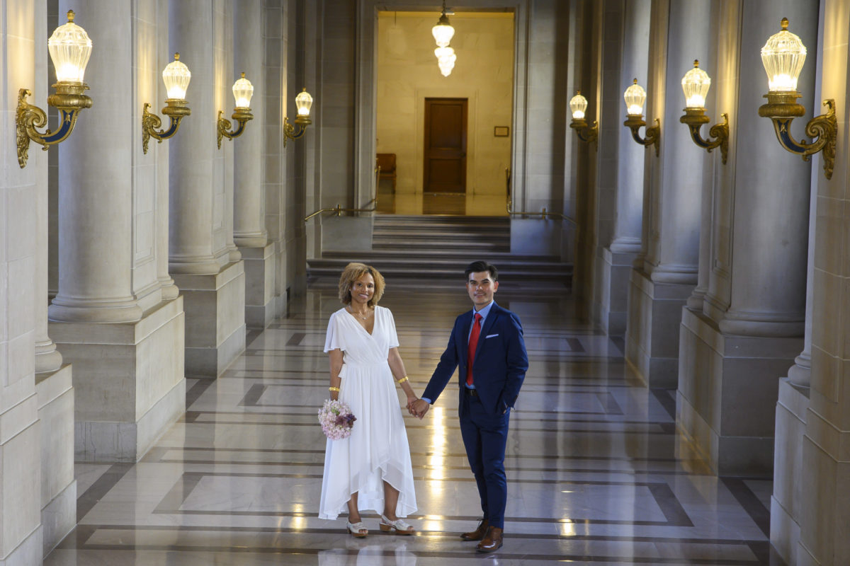2nd Floor of City Hall with bride and groom holding hands after their wedding.