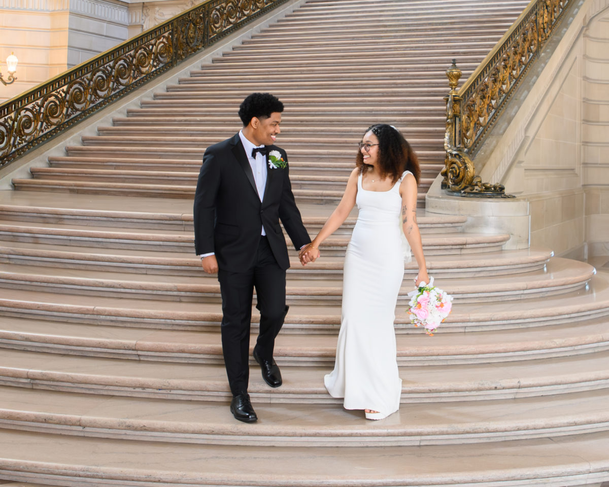 San Francisco city hall bride and groom walking down the Grant Staircase holding hands