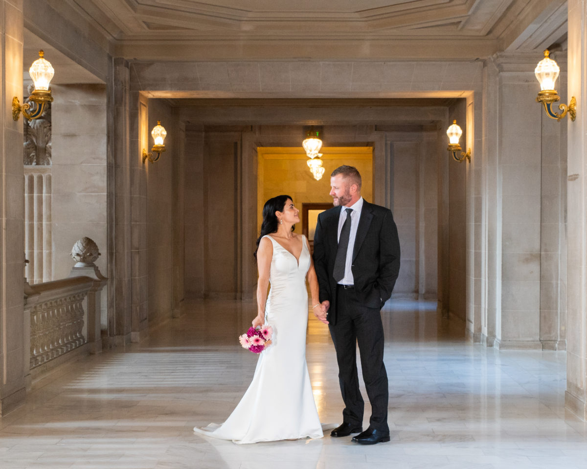 San Francisco city hall bride and groom pause after walking down the hallway on third floor