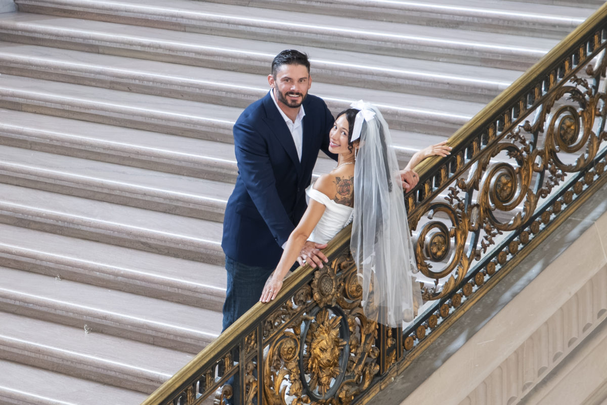 Brides wedding dress veil hangs over the railing at city hall