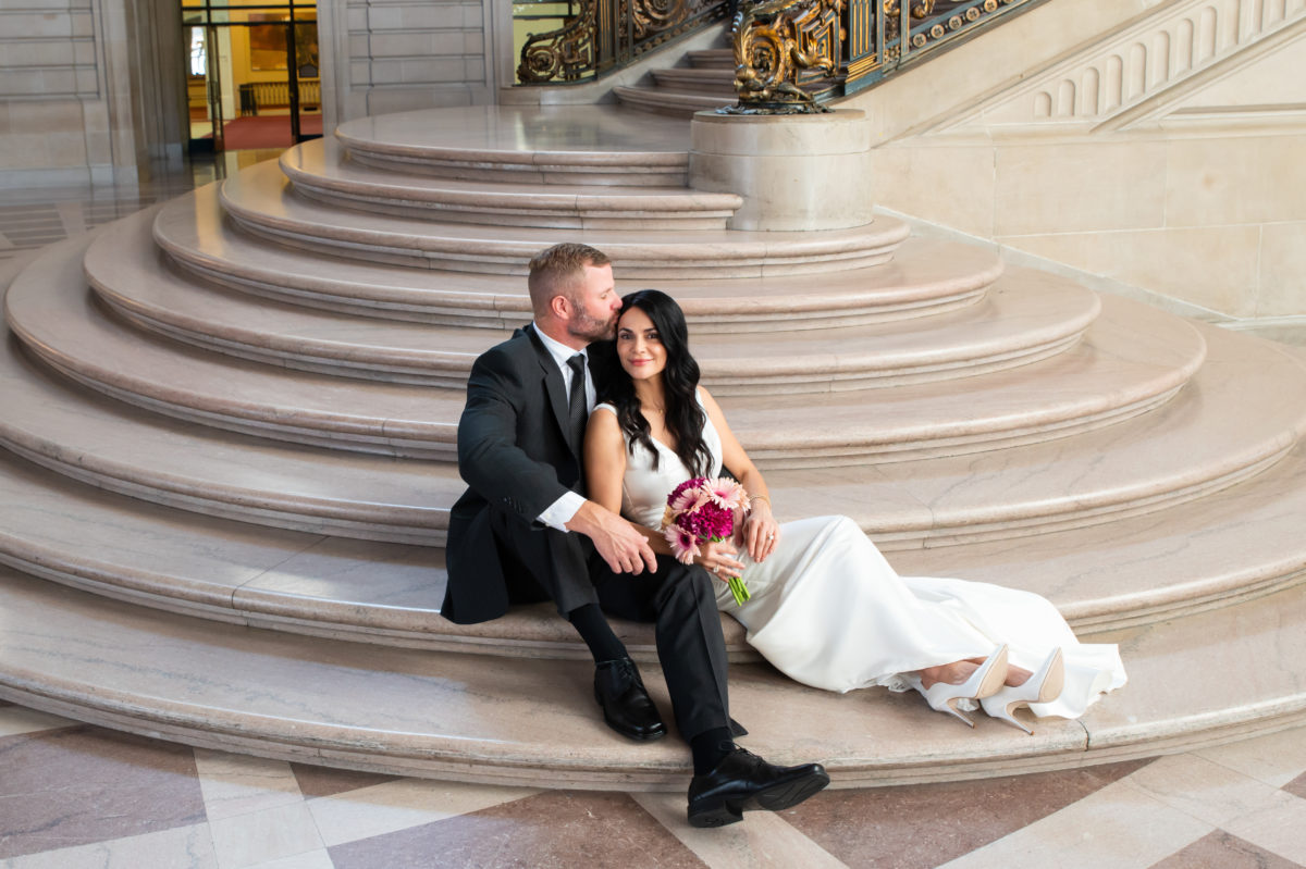 Bride and groom lounging and kissing on the Grand Staircase at city hall