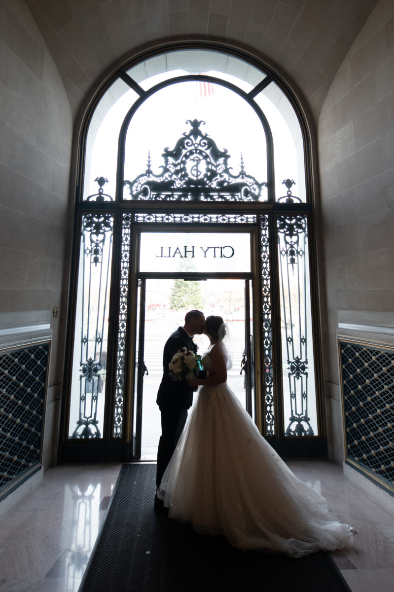 SF city hall bride and groom kiss as they leave the building