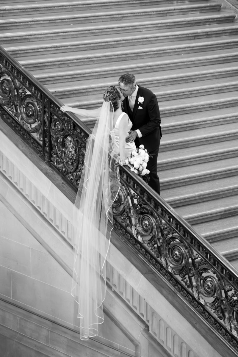 Brides veil drapes down the staircase railing at SF city hall